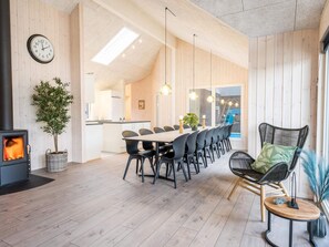 A modern interior with a dining area, a fireplace, and a view into the kitchen. - 5 Star Holiday Home in Norre Nebel (Norre Nebel)