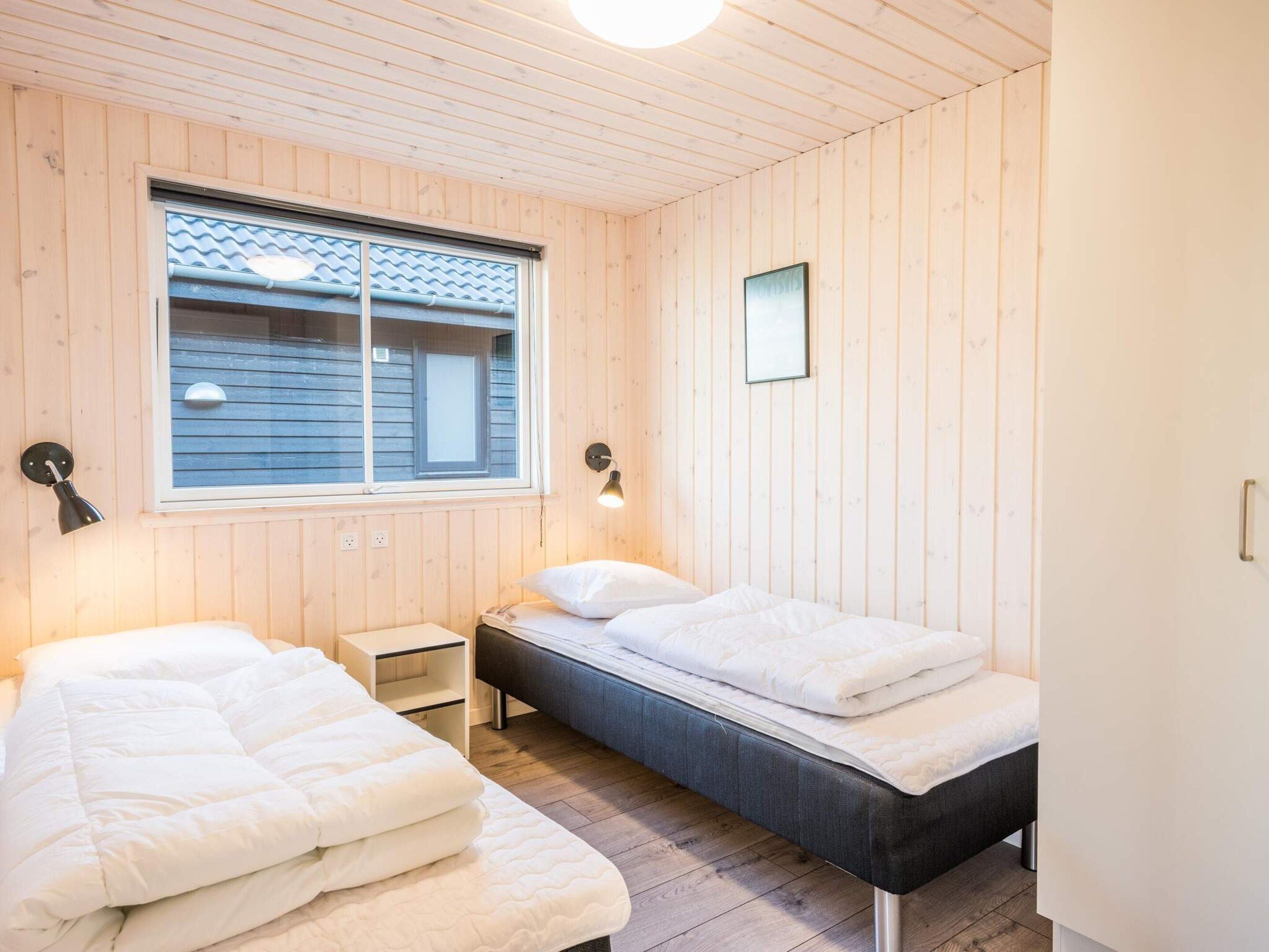 A room with two beds, a window, and a small bedside table.