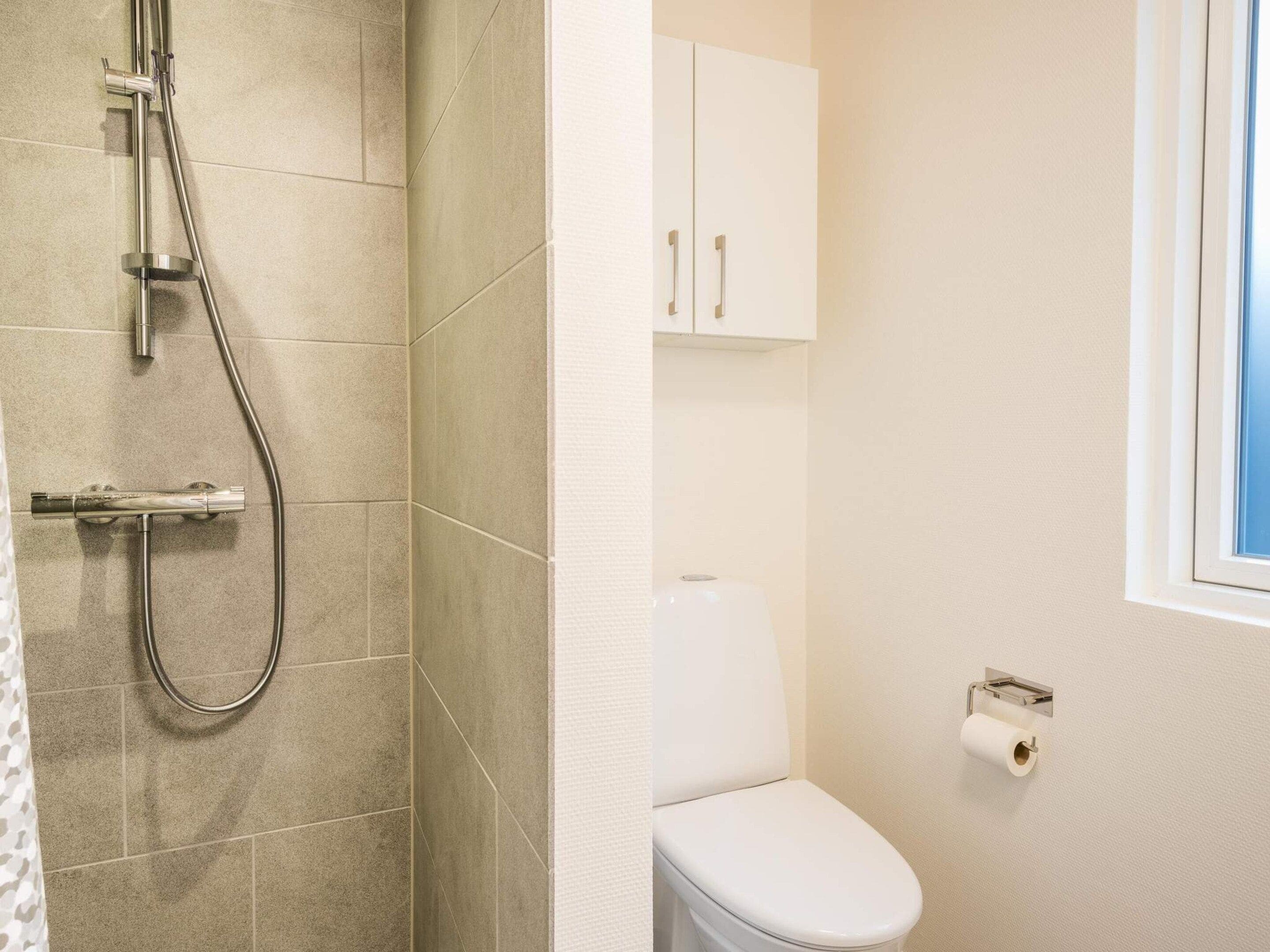 Une salle de bain avec une douche, des toilettes et un meuble de rangement.