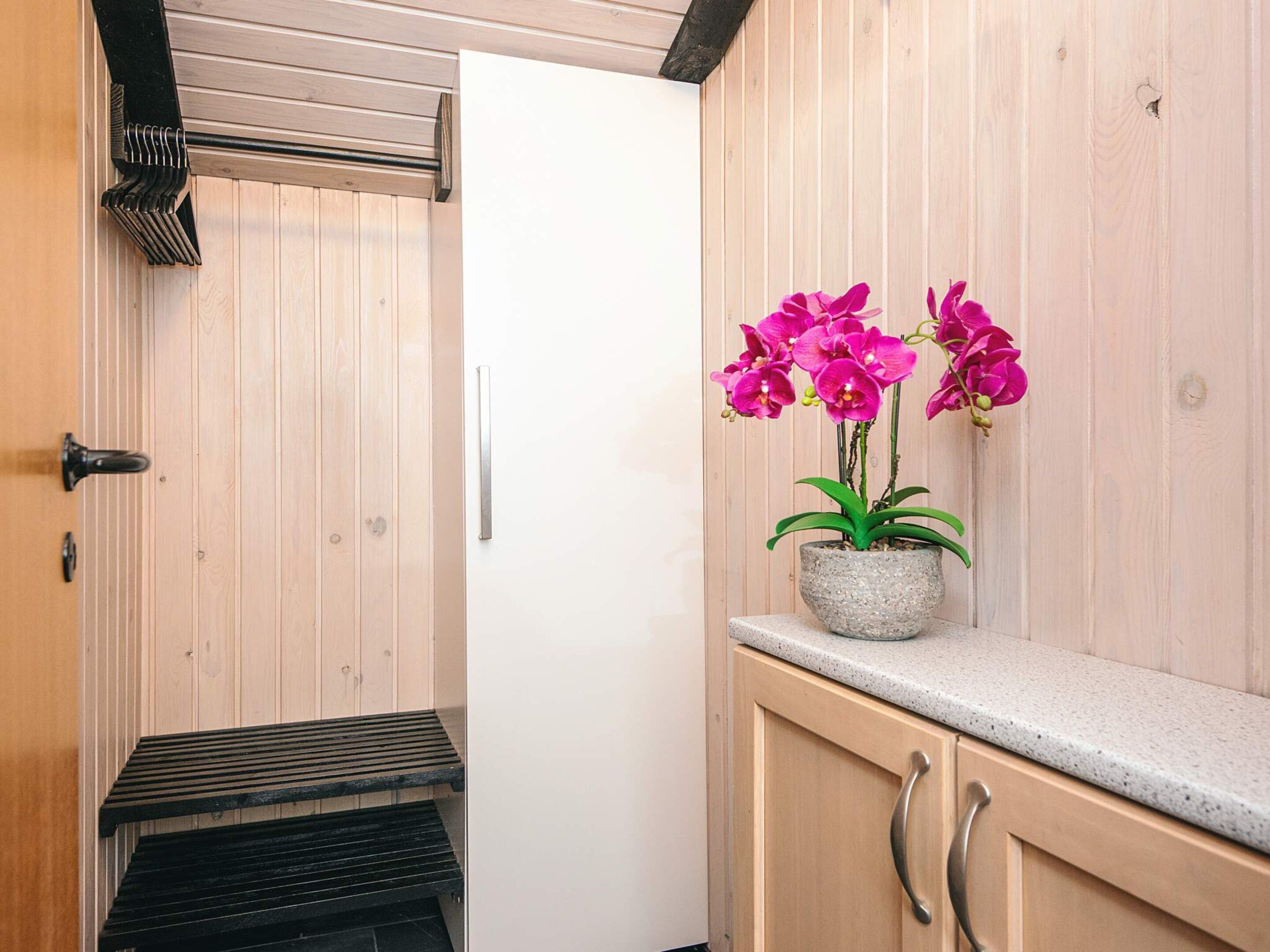 A bathroom with a wooden vanity, a sink, and a potted orchid plant.