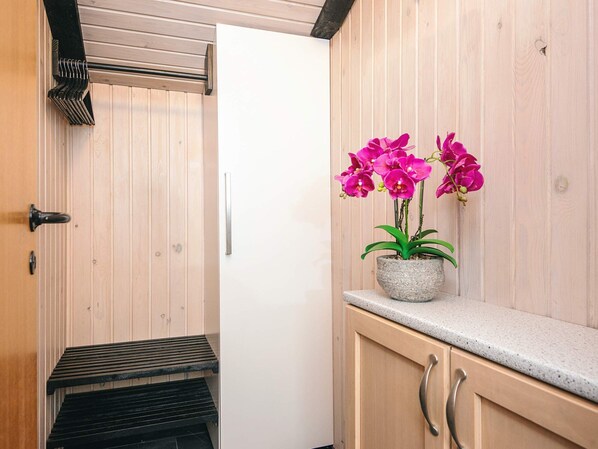 A bathroom with a wooden vanity, a sink, and a potted orchid plant. - 6 Person Holiday Home in Norre Nebel (Norre Nebel)