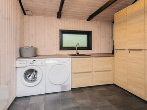 A laundry room with a washing machine, dryer, and wooden cabinets. - 6 Person Holiday Home in Norre Nebel (Norre Nebel)