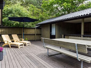 Relax on the deck with comfortable lounge chairs and a picnic table, shaded by a large umbrella.