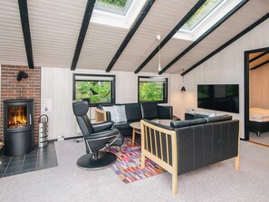 A modern living room with a fireplace, black leather furniture, a TV, and large windows. - 4 Star Holiday Home in Norre Nebel (Norre Nebel)