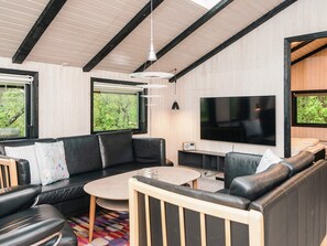 A modern living room with a sofa, coffee table, and TV. - 6 Person Holiday Home in Norre Nebel (Norre Nebel)
