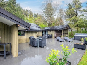 A covered outdoor patio with a dining area, lounge chairs, and a hot tub. - 4 Star Holiday Home in Norre Nebel (Norre Nebel)