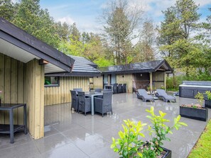 A covered patio area with outdoor furniture, a hot tub, and a wooden building structure. - 4 Star Holiday Home in Norre Nebel (Norre Nebel)