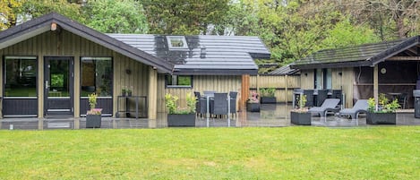 A modern building with a covered patio area, large windows, and outdoor seating.