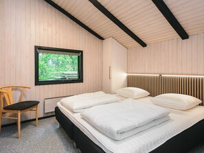 A bedroom with a bed, a chair, a window, and a wooden ceiling. - 6 Person Holiday Home in Norre Nebel (Norre Nebel)