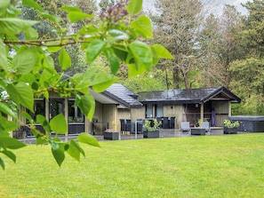 A modern building with a covered outdoor seating area and a grassy lawn. - 4 Star Holiday Home in Norre Nebel (Norre Nebel)