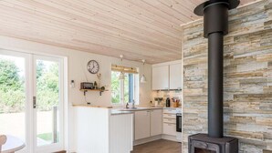 A modern kitchen with a central island, a built-in stove, and a stone accent wall. - Holiday Home in Tarm (Tarm)