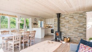 A spacious living area with a dining table, chairs, a sofa, and a stone wall. - Holiday Home in Tarm (Tarm)