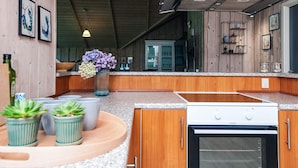 Una cocina moderna con gabinetes de madera, una campana extractora de acero inoxidable y un horno empotrado.