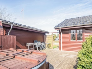 A wooden cabin with a covered patio area, a flagpole, and a fenced-in section with outdoor furniture. - 4 Star Holiday Home in Tarm (Tarm)