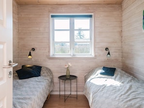 A room with two beds, a small table with a vase, and a window with a view of trees. - 4 Star Holiday Home in Tarm (Tarm)