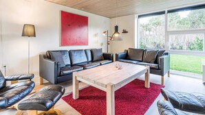 A modern living room with a wooden ceiling, two black leather sofas, a wooden coffee table, and a red rug. - 5 Person Holiday Home in Blavand (Blavand)