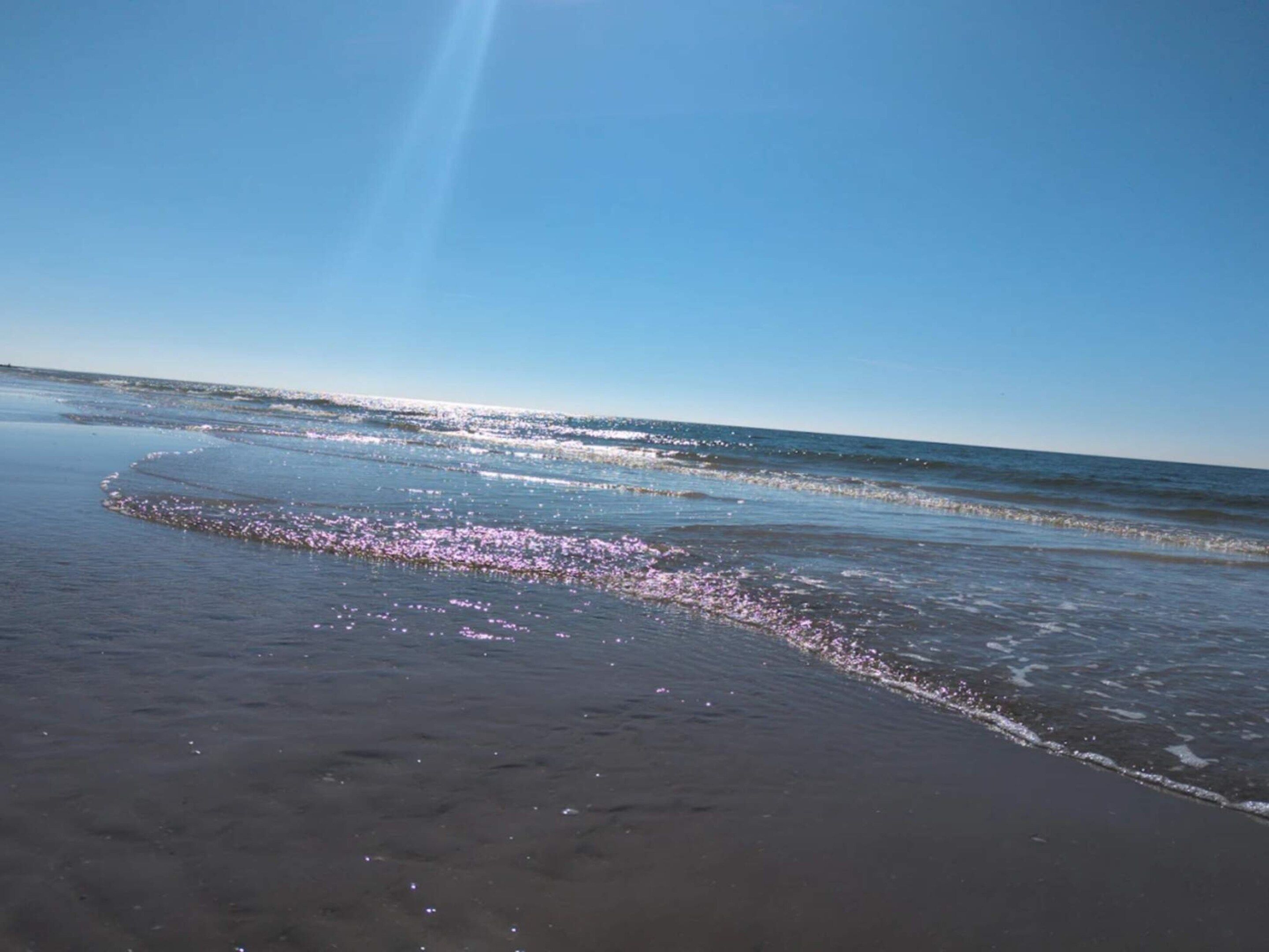 Una platja amb onades suaus i un cel clar.