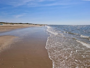 A beach with a wide sandy shore, gentle waves, and a clear sky. - 6 Person Holiday Home in Blavand (Blavand)