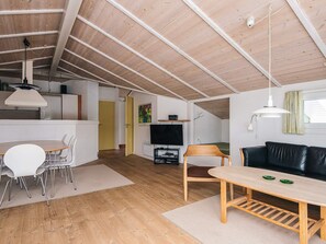 Een woonruimte in loft-stijl met een eethoek, een bank en een televisie.