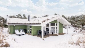 Una casa verde con un porche cubierto, una chimenea y una antena parabólica.