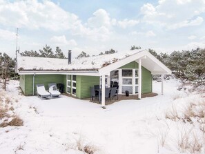 Une maison verte avec un porche couvert et une cheminée.
