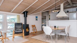 Una cocina moderna con una isla central, sillas blancas y una estufa negra.