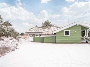 A green single-story house with a sloped roof, a small porch, and a visible chimney. - 6 Person Holiday Home in Blavand (Blavand)