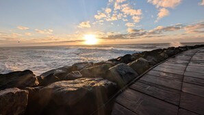 En träpromenad längs en stenig kust med havet i bakgrunden.