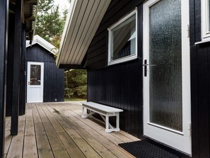 Une terrasse en bois avec un banc, une porte et une fenêtre.
