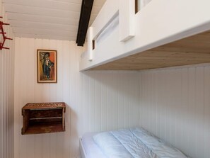 A bunk bed room with a wooden shelf and a framed picture on the wall.