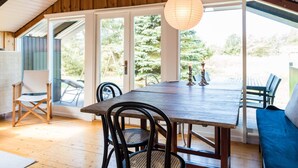 A dining area with a wooden table and chairs, a hanging paper lantern, and a view of the outdoors. - 6 Person Holiday Home in Blavand (Blavand)