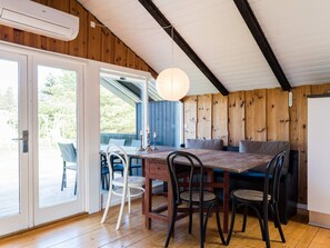 A wooden interior with a dining table, chairs, and a hanging light fixture.