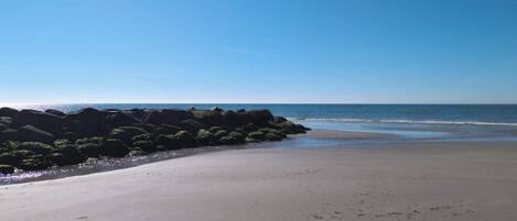 A beach with a rocky shoreline and calm waves.