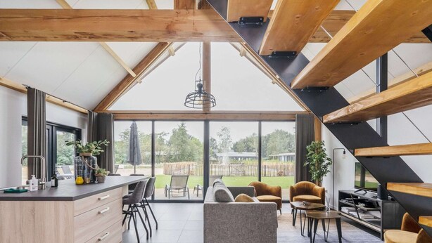 Cocina moderna con una isla grande, comedor con sillas y vistas al exterior.