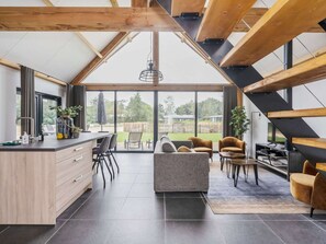 A modern kitchen with a large island, dining area with chairs, and a view of the outdoors.