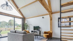Una sala de estar moderna con un sofá gris, techo de madera, televisor y una mesita.