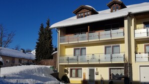 A multi-story building with balconies, a snow-covered roof, and a clear blue sky. - Ferienwohnung im Bayerischen Wald mit Balkon (Drachselsried)