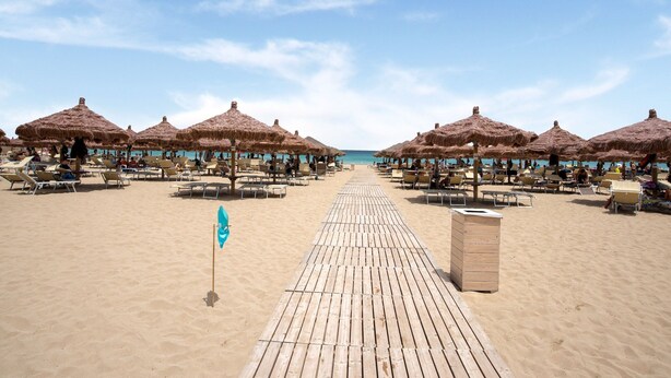 A beach with thatched umbrellas and sun loungers, a wooden walkway, and a clear view of the sea. - Simplistic Apartment in Reitani near Lido Beach (Noto)