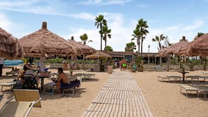 A beach with thatched umbrellas, sun loungers, and a wooden walkway. - Simplistic Apartment in Reitani near Lido Beach (Noto)