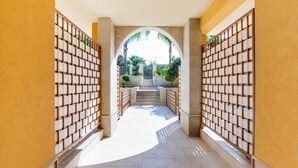 A corridor with a tiled floor, a central archway, and a staircase leading to an outdoor area with greenery. - Simplistic Apartment in Reitani near Lido Beach (Noto)