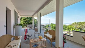 A spacious balcony with wicker furniture, a table with books and a bowl of fruit, and a view of the cityscape. - Holiday Home Near Urbino & Beaches (Tavullia)