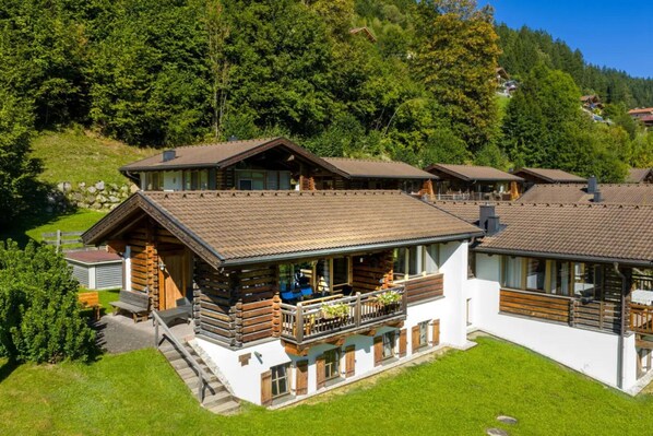 A chalet-style hotel with multiple guest rooms, a central courtyard, and a mountainous backdrop. - Rustic Chalet in a Holiday Village (Wald im Pinzgau)