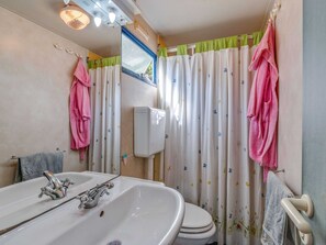 A bathroom with a sink, two faucets, a toilet, and a shower curtain with a floral pattern.