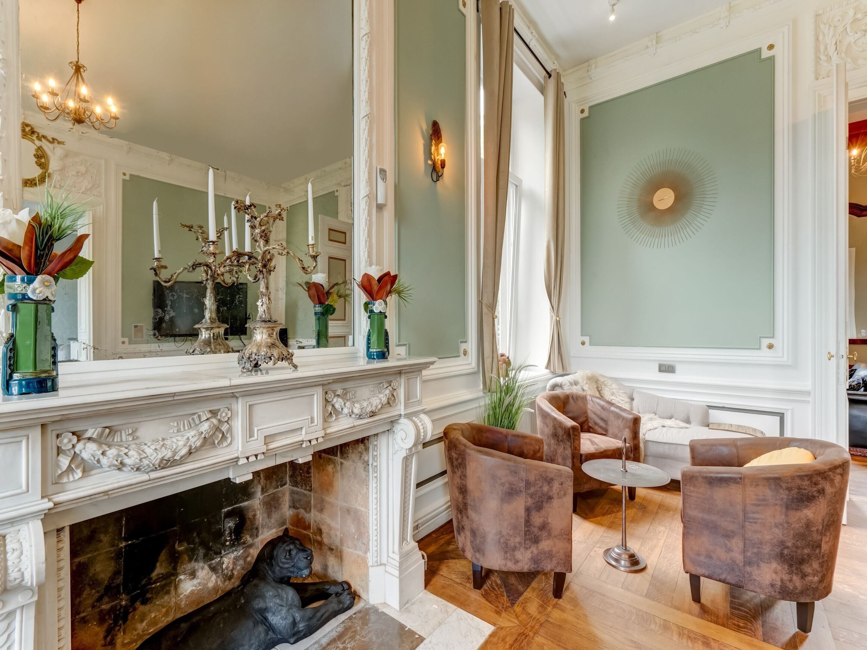 Un salon spacieux doté d’une cheminée, de meubles élégants et d’un grand miroir.
