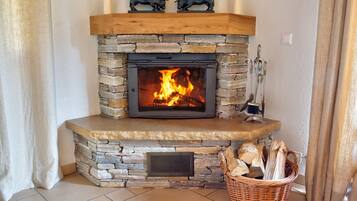 A stone fireplace with a fire, a wooden mantel, and two bull statues.
