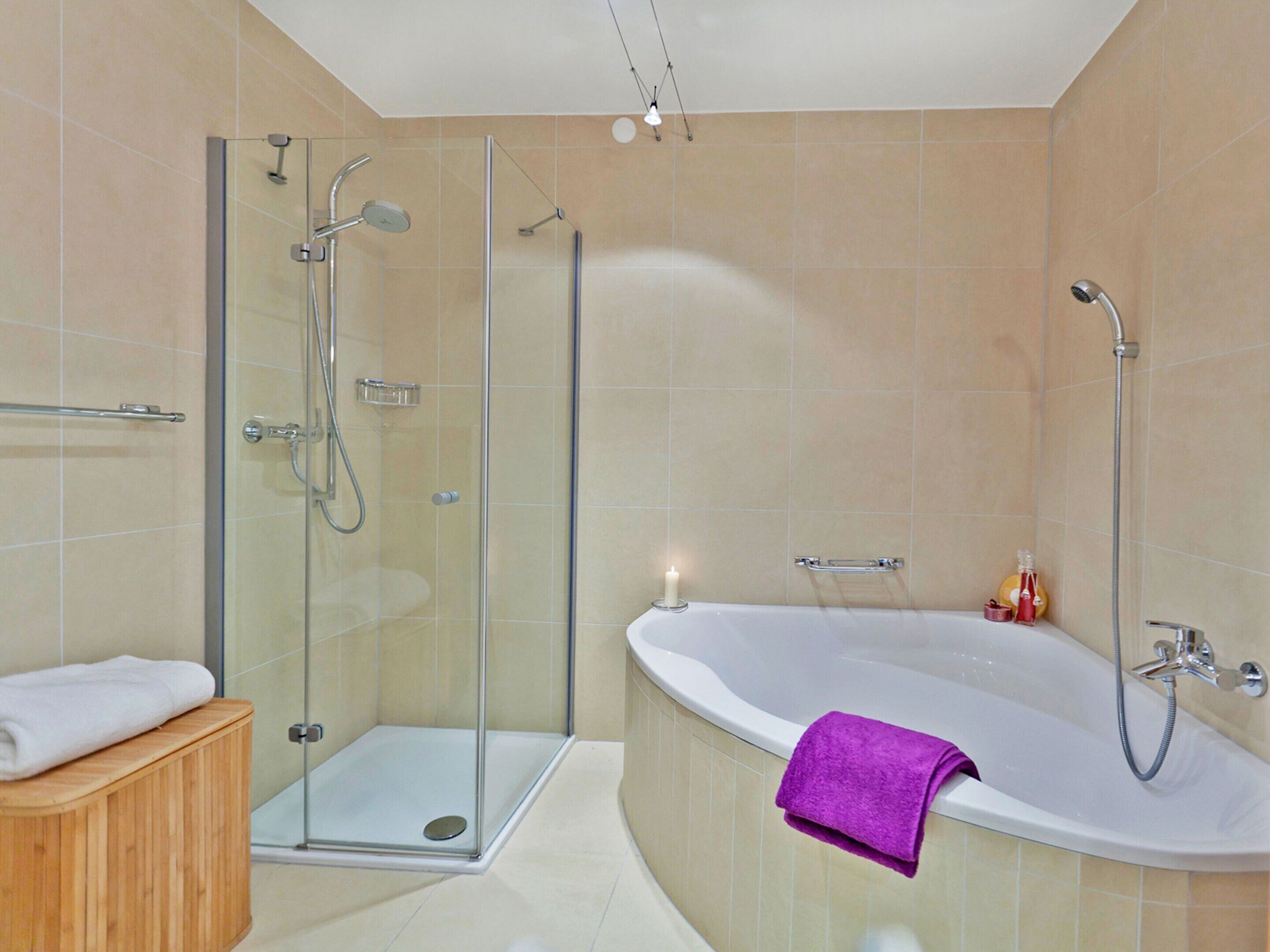 Une salle de bain moderne avec une douche à parois de verre, une baignoire sur pieds et un meuble-lavabo en bois.