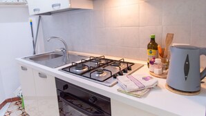 A compact kitchen with a gas stove, sink, and modern cabinetry. - Vue Merveilleuse Apartment (Castellammare del Golfo)