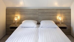 A double bed with two bedside tables, each with a lamp. The room has a wooden headboard and a plain white ceiling. - Modern Holiday Home, Near the Sea (Bredene)