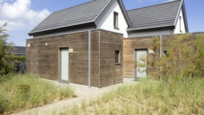 A modern two-story house with a sloped roof, wooden siding, and numbered doors. - Modern Holiday Home, Near the Sea (Bredene)