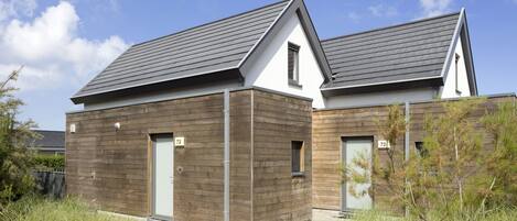 Une maison moderne à deux étages, dotée d’un toit en pente, d’un revêtement en bois et de portes numérotées.